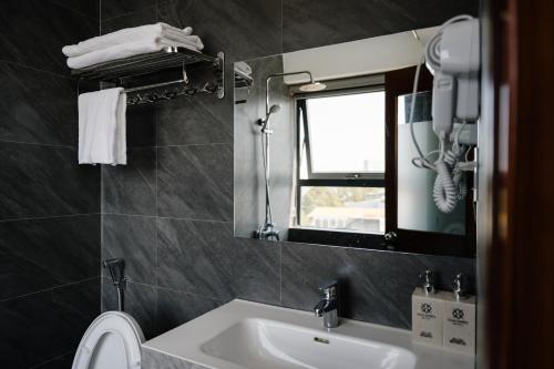 a bathroom with a sink and a mirror and a toilet at Khách Sạn Hạo Nhiên in Buon Ma Thuot