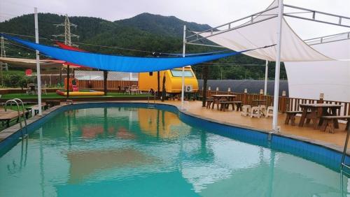 a swimming pool with a tent over it with tables and chairs at Jnj Village in Suncheon
