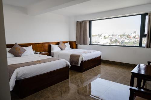 a hotel room with two beds and a large window at Khách Sạn Hạo Nhiên in Buon Ma Thuot