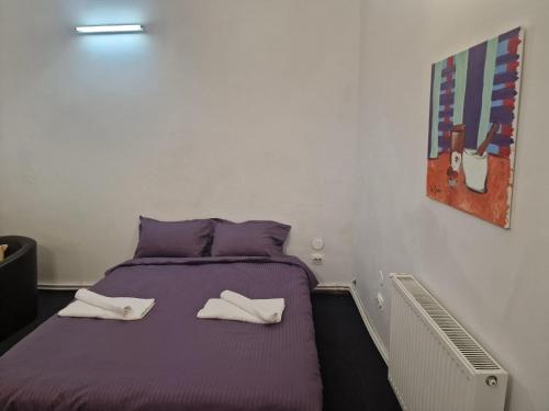 a purple bed with two white towels on it at Eroilor Downtown Studio in Cluj-Napoca