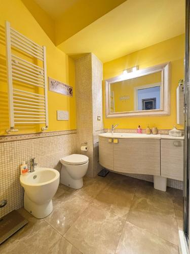 a yellow bathroom with a toilet and a sink at Al Colosseo Quadrato in Rome