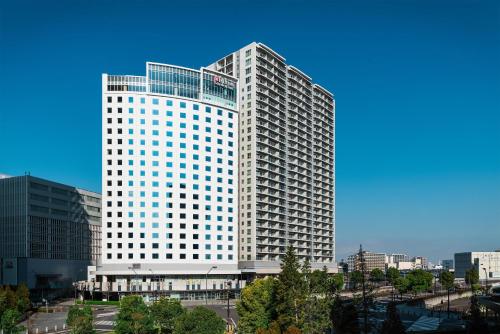 a tall white building in a city at Hilton Garden Inn Yokohama Minatomirai in Yokohama