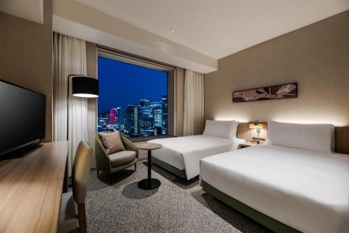a hotel room with two beds and a window at Hilton Garden Inn Yokohama Minatomirai in Yokohama
