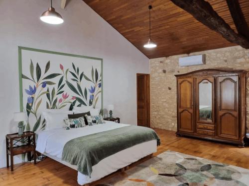 a bedroom with a large bed with a painting on the wall at SOLASI - Gîte et Chambres D'hôtes in Blanquefort-sur-Briolance