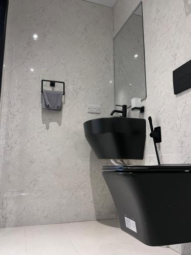 a bathroom with a black toilet and a sink at Mayfair Hotel in Dar es Salaam