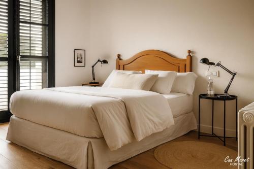 a bedroom with a large white bed with two lamps at Hostal Can Maret in Vilademuls