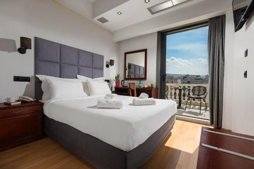 a bedroom with a large bed and a large window at Athens Odeon Hotel in Athens
