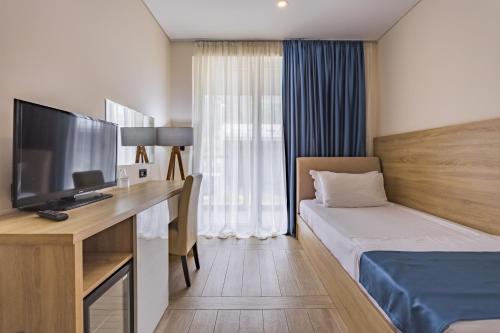 a hotel room with a bed and a desk with a television at Hotel Franca Tivat in Tivat