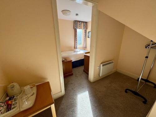 a small room with a bedroom with a bed and a table at Purbeck House Hotel & Louisa Lodge in Swanage