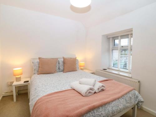 a bedroom with a bed with two lamps and a window at 27 Kingshead Street in Pwllheli