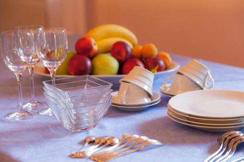 una mesa con tenedores y vasos y un plato de fruta en B&B Borgo San Vito, en Ronchi dei Legionari