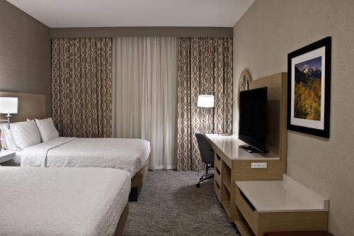 a hotel room with two beds and a desk with a television at Hampton Inn & Suites Denver-Speer Boulevard in Denver