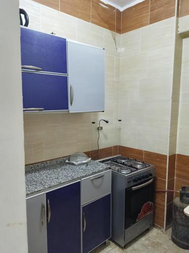 a kitchen with a stove and blue cabinets at Guest House Science 1 in Marsa Alam City