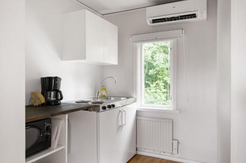a white kitchen with a sink and a window at Lidö Värdshus in Lidö