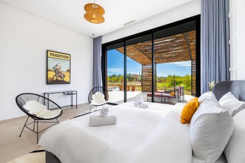 a bedroom with a large white bed and chairs at Citrus Bloom Manor Marrakech in Oulad Mazoug