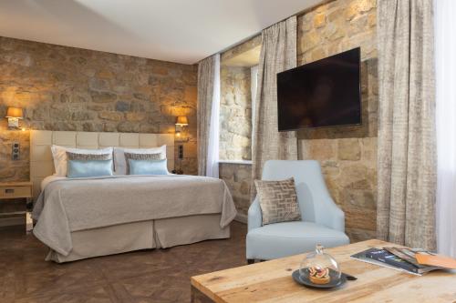 a bedroom with a bed and a tv and a chair at Domaine de la Klauss & Spa, Restaurant Gastronomique Le K in Montenach