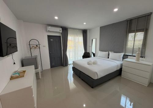 a bedroom with a white bed and a television at I am Daily Mansion in Ban Phan Sadet Nai