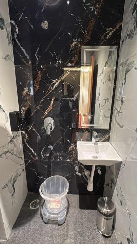 a bathroom with a sink and a black marble wall at Hotel Golden Bird in Dabok