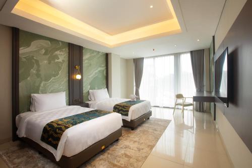 a hotel room with two beds and a television at Louis Kienne Hotel Cikarang in Cikarang