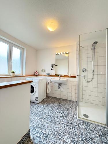 a bathroom with a shower and a sink and a washing machine at Haus Charlotte mit Meerblick in Fehmarn