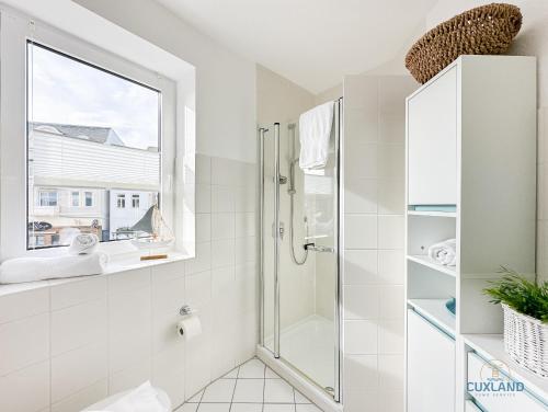 a white bathroom with a shower and a window at Marina Liebe in Cuxhaven