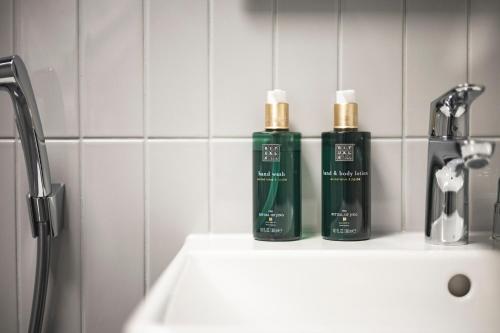 two bottles ofodorizers sitting on a sink in a bathroom at The Folks Hotel Konepaja in Helsinki
