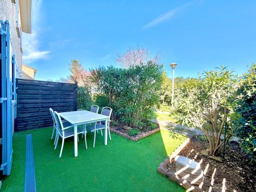 a patio with a table and chairs on the grass at La salamandre bleue : 4 pers piscine à Calvisson in Calvisson