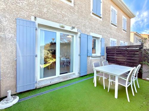 a patio with a table and chairs in front of a building at La salamandre bleue : 4 pers piscine à Calvisson in Calvisson