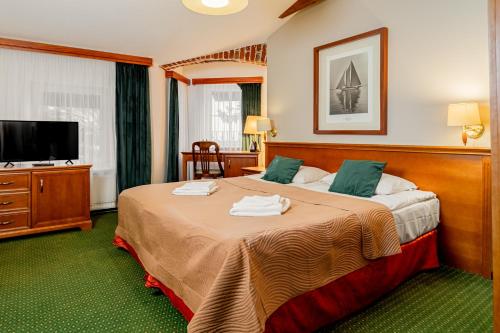 ein Hotelzimmer mit zwei Betten und einem Flachbildfernseher in der Unterkunft Meduza Hotel & Spa in Mielno