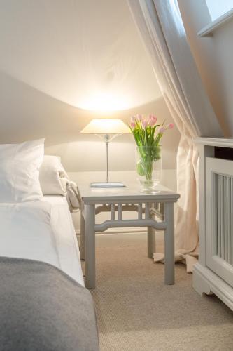 a bedroom with a table with a vase of flowers on it at Haus Peacock in Kampen