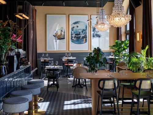 a restaurant with tables and chairs and chandeliers at Jadran Heritage Hotel, Valamar Collection in Poreč