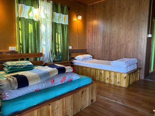 two beds in a room with wooden walls at Soshing Homestay in Ravangla