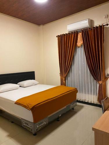 ein Schlafzimmer mit einem Bett und einem Fenster mit Vorhängen in der Unterkunft Aco Borneo Hotel in Malinau