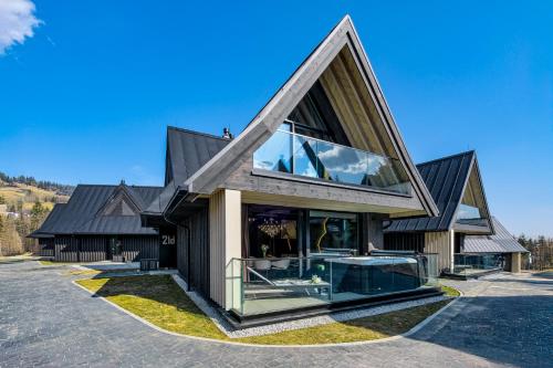 a house with a triangular roof with glass windows at Crystal Peak Villas z prywatnym jacuzzi, Odkryj-Zakopane in Kościelisko