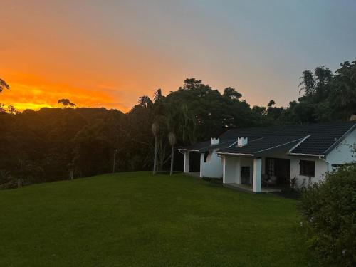 a house with a green yard in front of a sunset at Bellevue Guest Lodge in Southbroom