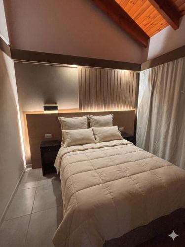 a bedroom with a large bed with white sheets and pillows at Cabaña julian in Villa Berna