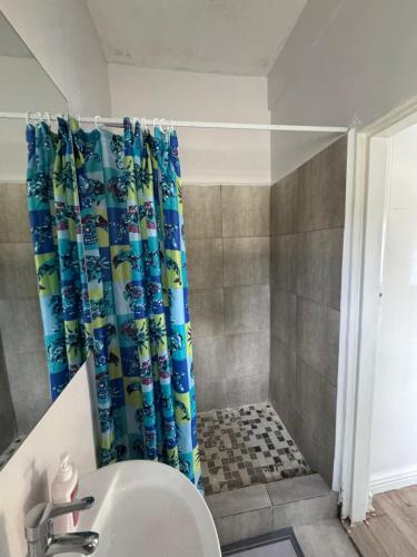 a bathroom with a shower curtain and a sink at The Luxe Studio in Lusaka