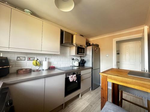 a kitchen with white cabinets and a stove top oven at Castle View, Cosy Stay in Strood
