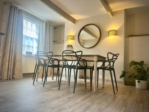 a dining room table with chairs and a mirror at Stay at No12 in Lyme Regis