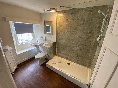 a bathroom with a shower with a toilet and a sink at The Cavendish Arms in Cartmel