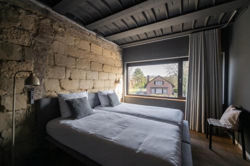 a bedroom with a bed and a brick wall at K-Kanne in Kanne