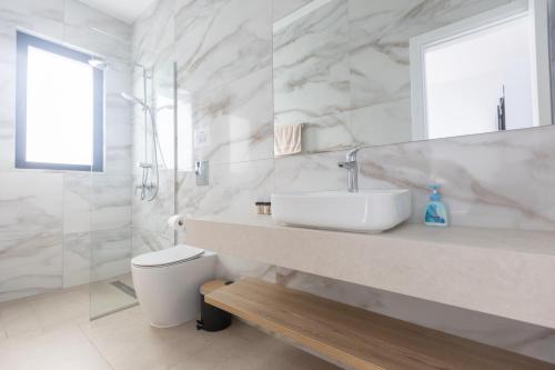 a white bathroom with a sink and a toilet at Orea Luxury Villas in Ayia Napa