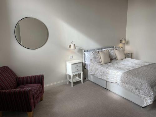 a bedroom with a bed with a mirror and a chair at Stillington Retreat in Stillington