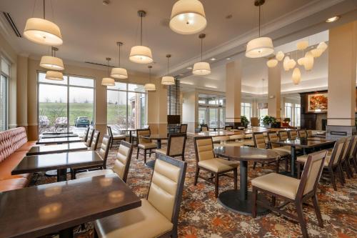 a restaurant with tables and chairs and windows at Hilton Garden Inn St. Louis Airport in Berkeley