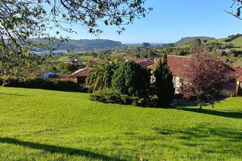 a field of green grass with houses and trees at El Verdecillo de Rodiles, Villaviciosa in Selorio