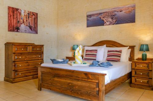 a bedroom with a large bed and a dresser at Il-Kampnar Gozo Farmhouse with Private Pool in Sannat