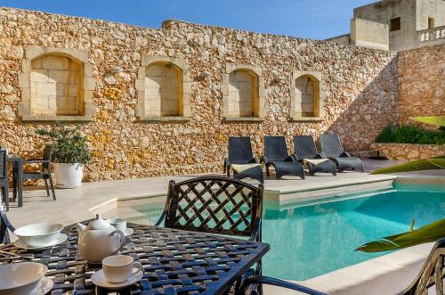 a patio with a table and chairs next to a pool at Il-Kampnar Gozo Farmhouse with Private Pool in Sannat