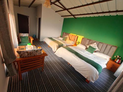 two beds in a room with a green wall at Neo Resort in Kanatal