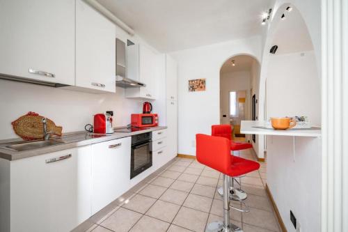 a kitchen with white cabinets and a red chair at Dolce Teresa in Mandello del Lario