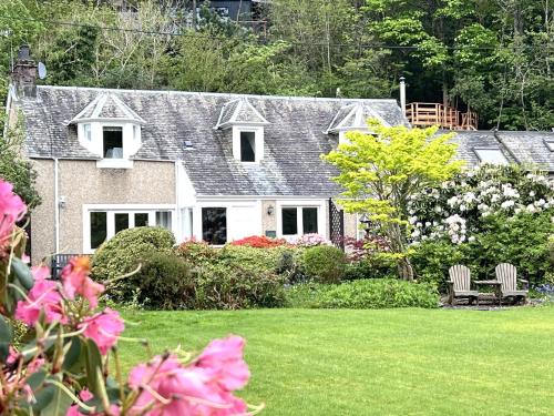a house with a yard with pink flowers at The Coach House in Saint Fillans